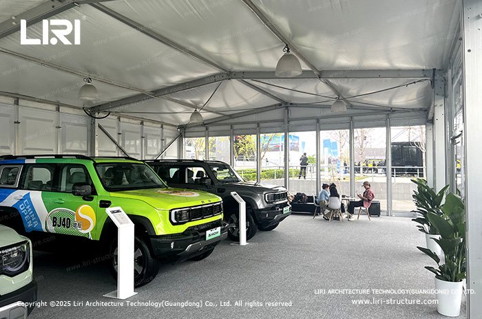 Medium-sized exhibition tent interior with vehicles on display and seating area